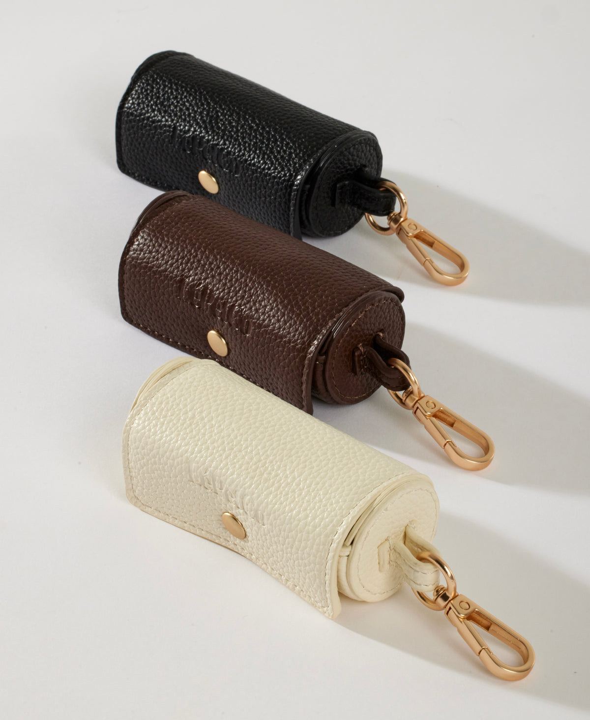Dog poop bag holders in Bone, Cacao and Onyx with brushed gold clips